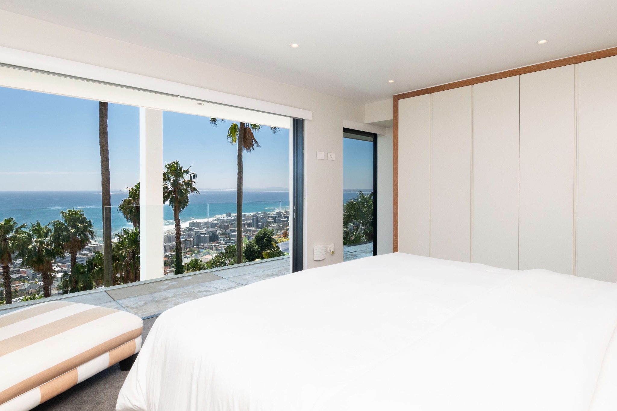 A bright bedroom with large windows and an ocean outlook